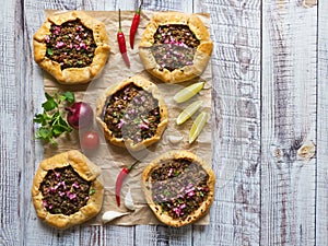 Arabian opened meat pies on white wood background.