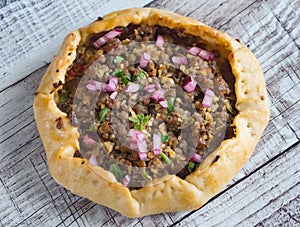 Arabian opened meat pies on white wood background.