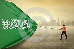 Arabian person dragging flag of Saudi Arabia