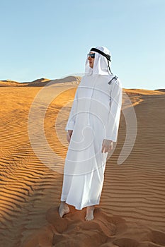 Arabian sheikh in long white dress closeup in the middle of Dubai desert