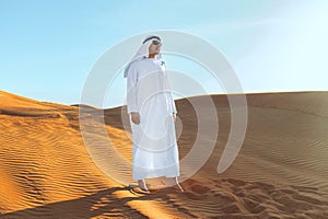 Arabian sheikh in long white dress closeup in the middle of Dubai desert