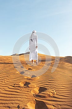 Arabian sheikh in long white dress closeup in the middle of Dubai desert