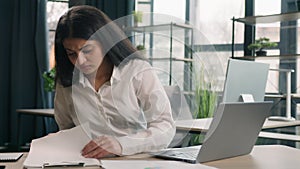 Arabian stressed businesswoman gen z Indian business woman working in office with computer laptop and paperwork problem