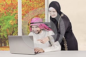 Arabian wife looking at her husband working