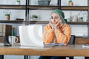 arabian woman in headkerchief sitting with photo