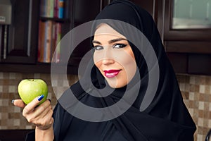 Arabian woman holding an apple in the kitchen