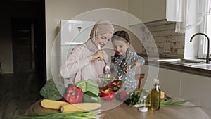 Arabian woman mother teach Caucasian small cute daughter preparing healthy vegetarian food