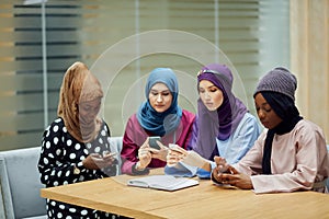 Arabian young women watching on cellphone musical video clip standing together.