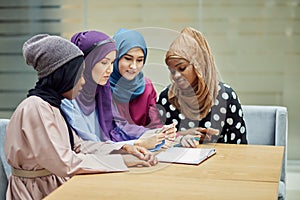 Arabian young women watching on cellphone musical video clip standing together.