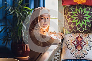 Arabian young muslim woman sitting in a cafe.