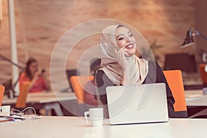Arabic business woman wearing hijab, working in startup office.