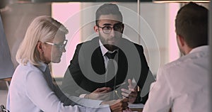 Arabic businessman consulting handshaking caucasian client at group negotiations