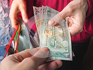 Arabic coins of dirhams. Curled banknotes in his hands.