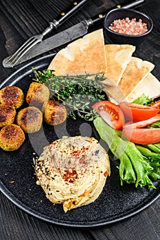 Arabic cuisine Hummus chickpea, falafel, pita bread and fresh vegetables. Black wooden background. Top view