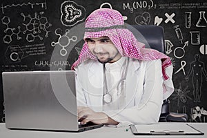 Arabic doctor uses laptop in laboratory