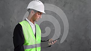 Arabic engineer man with a phone. Builder with smartphone on a grey background. Hard hat and construction uniforms on