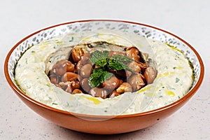 Arabic food Hummus with parsley in a traditional bowl.