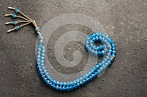 Arabic letter wav made with blue rosary on gray rustic background