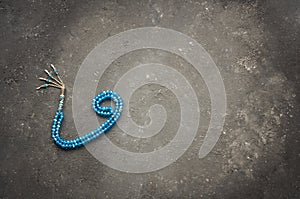 Arabic letter wav made with blue rosary on gray rustic background