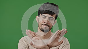 Arabic man hispanic guy standing posing on green studio background shows stop gesture prohibition sign crossing arms in