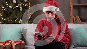 Arabic man paying online by credit card for Christmas gifts using smartphone, shopping online, enjoying winter holiday