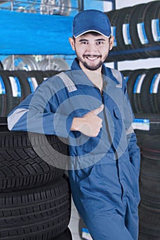 Arabic mechanic with tires shows thumb up