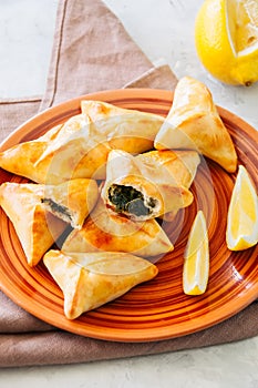 Arabic and middle eastern food concept. Fatayer sabanekh - traditional arabic spinach triangle hand pies dates and tea on a white