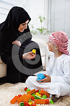 Arabic mother and son together at home playing with toys.