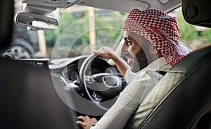 Arabic Muslim businessman driving a car wearing a Keffiyeh