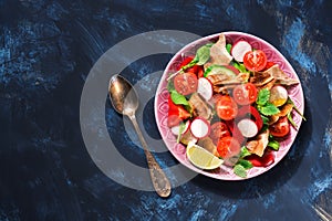 Arabic salad of fresh vegetables with bread Fattoush on a blue background. Top view, copy space