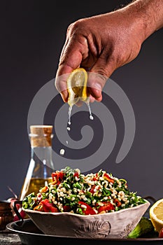 Arabic Salad Tabbouleh close up in bowl, splashes of lemon juice, Traditionally food Levantine vegetarian salad with parsley, mint