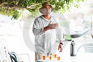 Arabic senior man talking and gesticulating near table with traditional tea.