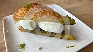 Arabic sweet baklava or baklawa served with icecream on white porcelain plate on restaurant table