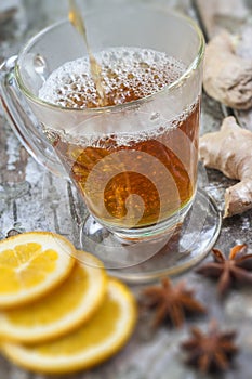 Arabic tea in traditional glass with mint, cinnamon, anise stars on grey wooden background