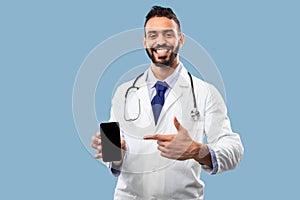 Arabic Therapist Man Showing Phone With Blank Screen, Blue Background