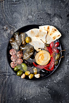Arabic traditional cuisine. Middle Eastern meze platter with pita, olives, hummus, stuffed dolma, labneh cheese balls in spices.