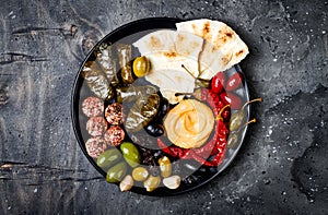 Arabic traditional cuisine. Middle Eastern meze platter with pita, olives, hummus, stuffed dolma, labneh cheese balls in spices.