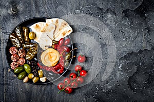 Arabic traditional cuisine. Middle Eastern meze platter with pita, olives, hummus, stuffed dolma, labneh cheese balls in spices.