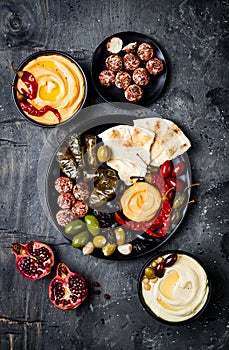 Arabic traditional cuisine. Middle Eastern meze platter with pita, olives, hummus, stuffed dolma, labneh cheese balls in spices.