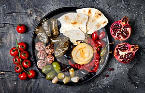 Arabic traditional cuisine. Middle Eastern meze platter with pita, olives, hummus, stuffed dolma, labneh cheese balls in spices.