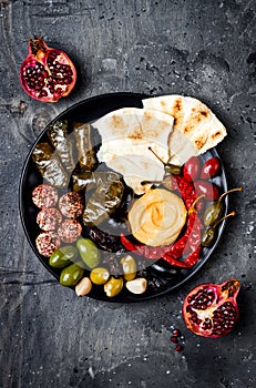 Arabic traditional cuisine. Middle Eastern meze platter with pita, olives, hummus, stuffed dolma, labneh cheese balls in spices.