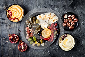 Arabic traditional cuisine. Middle Eastern meze platter with pita, olives, hummus, stuffed dolma, labneh cheese balls in spices.