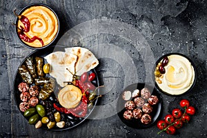 Arabic traditional cuisine. Middle Eastern meze platter with pita, olives, hummus, stuffed dolma, labneh cheese balls in spices.