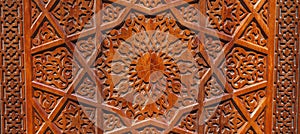 Arabic Uzbek Islamic patterns arabesque ornament on brown wooden carved door in Uzbekistan close up