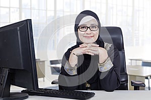 Arabic woman with headscarf smiling in office