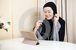 Arabic woman using tablet pc computer. Southeast Asian student at home. Muslim teenage girl living lifestyle.