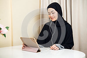 Arabic woman using tablet pc computer. Southeast Asian student at home. Muslim teenage girl living lifestyle.