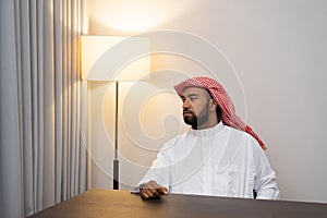 Arabs in turbans look to the side while sitting behind a desk