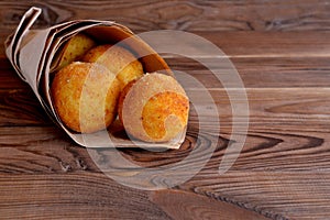 Arancini balls in paper on brown wooden background photo