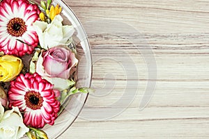 Arangement with roses and gerberas flowers in the glass bowl wit